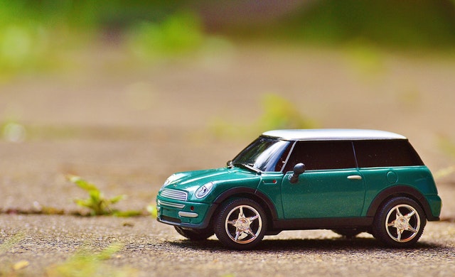 Zelený model auta položený na betónovej ceste